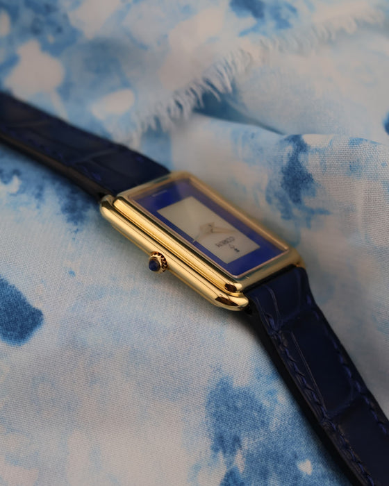 Sapphire cabochon crown on Corum 18K yellow gold tank watch, viewed from the side