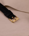 Close-up of original Piaget gold buckle from the top, attached to the black leather strap.