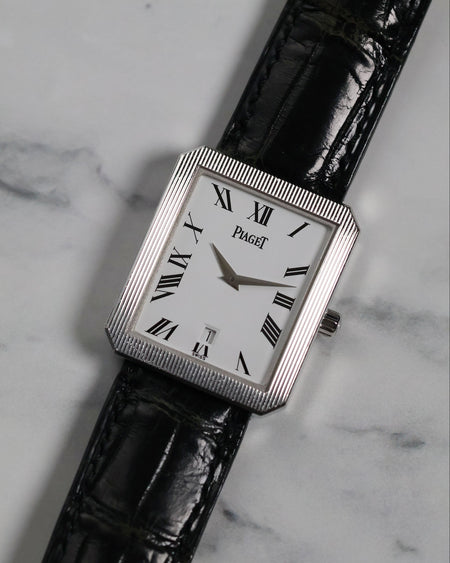 Frontal view of Piaget Ref. 26354 in 18K white gold with fluted bezel and Roman numeral dial on black leather strap.