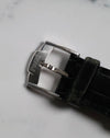Top view of original Piaget-signed 18K white gold buckle attached to black leather strap.