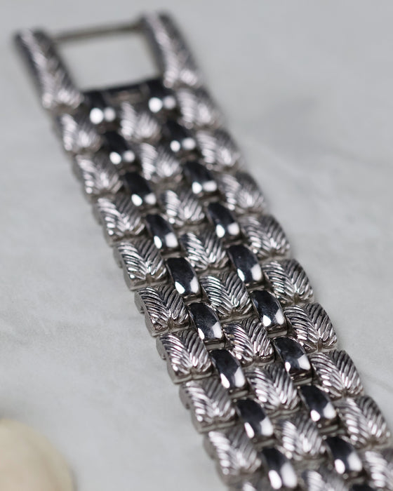 Detailed macro of the feather-pattern engraved white gold bracelet links.