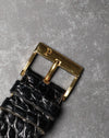 Original 18K yellow gold Piaget buckle viewed from above on black leather strap.
