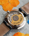 Close-up of Chaumet signed rotor through transparent caseback, 18K white gold watch movement detail.