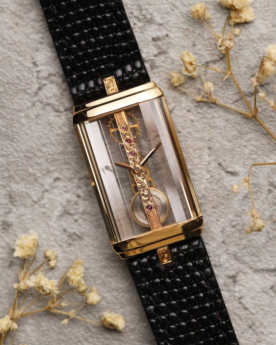 Full view of the Corum Golden Bridge 13150 on black textured leather strap, showcasing the rectangular 18k yellow gold case with transparent sapphire sides and the linear skeletonized movement visible through the front.