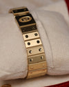 Angled shot of the Cartier Santos Carrée gold bracelet on a cushion, highlighting the uniform brushed links and screw-decoration pattern.