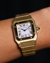 Wrist shot of the Cartier Santos Carrée Or Massif Ref. 2960 in solid 18K yellow gold, showing the watch worn on the wrist with the bright white Roman dial and blue cabochon crown.
