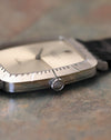 Macro side detail of Rolex Cellini crown with Rolex coronet engraving and fluted edge, set against brushed white gold case.