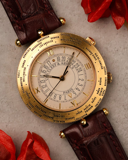 Van Cleef & Arpels Traveller world time watch in 18K yellow gold, featuring engraved city bezel and multi-layer dial with 24-hour ring