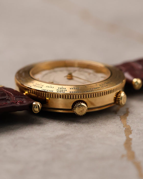 Side profile of Van Cleef & Arpels Traveller highlighting slim 18K gold case, engraved world time bezel, and signed crowns