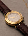 Three-quarter view of Van Cleef & Arpels Traveller world time watch with applied Roman numerals and gold hands