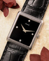 Piaget Ref. 9152 in 18K white gold with woven textured case, black onyx dial and diamond markers, photographed flat lay with black leather strap and red leaves.