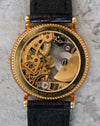 Universal Genève skeleton watch caseback showing the automatic micro-rotor movement in 18K yellow gold, with engraved brand markings and coin-edge case detailing.