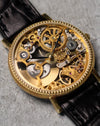 Angled close-up of the skeletonised dial, revealing the balance assembly, gear train, and contrasting gold and steel components.