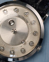 Detailed dial close-up showing diamond hour markers, minute track dots, and mystery time display