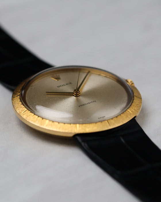 Angled macro of silver dial with sunburst finish, baton hands, and “Precision” text