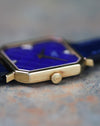 Low angle macro of lapis tile dial with diamond markers and dauphine hands in yellow gold case