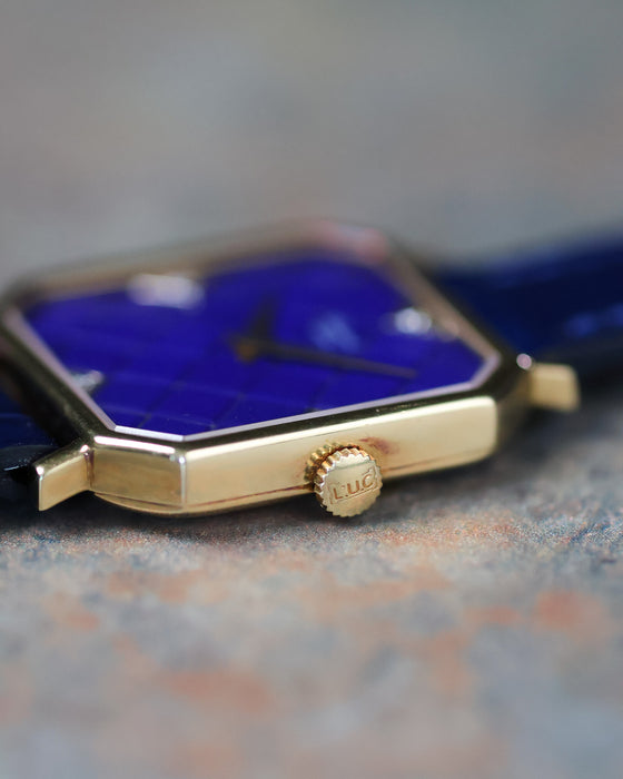 Low angle macro of lapis tile dial with diamond markers and dauphine hands in yellow gold case