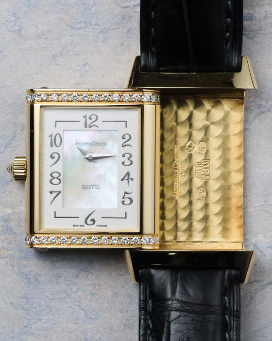 Reverso case partially flipped showing front mother-of-pearl dial alongside guilloché inner case surface.