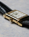 Crown detail with cabochon-style setting on a polished yellow gold case.