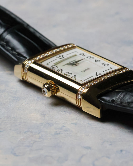 Crown detail with cabochon-style setting on a polished yellow gold case.
