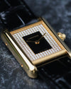Close-up angled view of Cartier Tank LC yellow gold case with black lacquer dial and diamond-set surround.