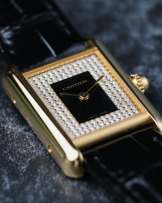 Close-up angled view of Cartier Tank LC yellow gold case with black lacquer dial and diamond-set surround.