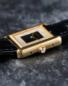 Macro shot of crown with faceted cabochon on Cartier Tank yellow gold case.