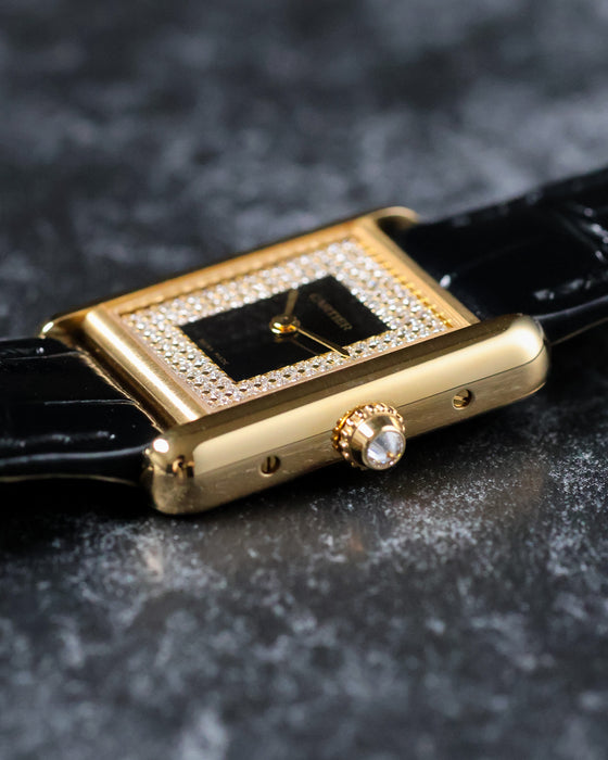 Macro shot of crown with faceted cabochon on Cartier Tank yellow gold case.