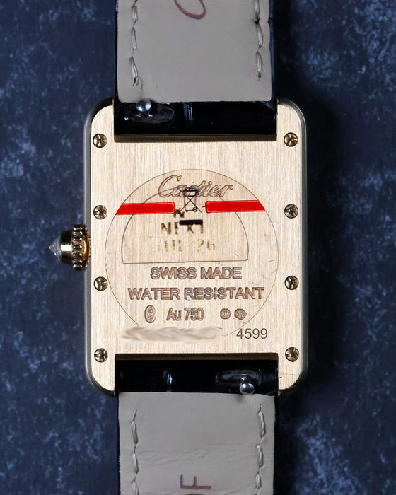 Caseback of Cartier Tank in brushed yellow gold with engraved markings and screws visible.