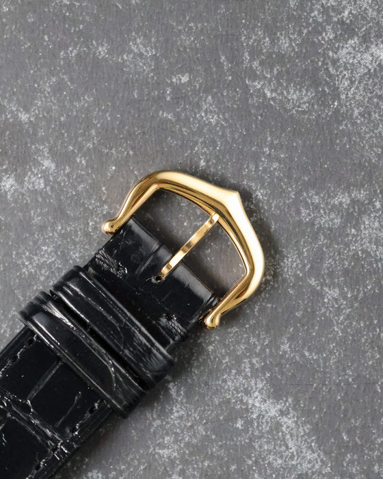 Close-up of original Cartier 18k yellow gold buckle on black leather strap.