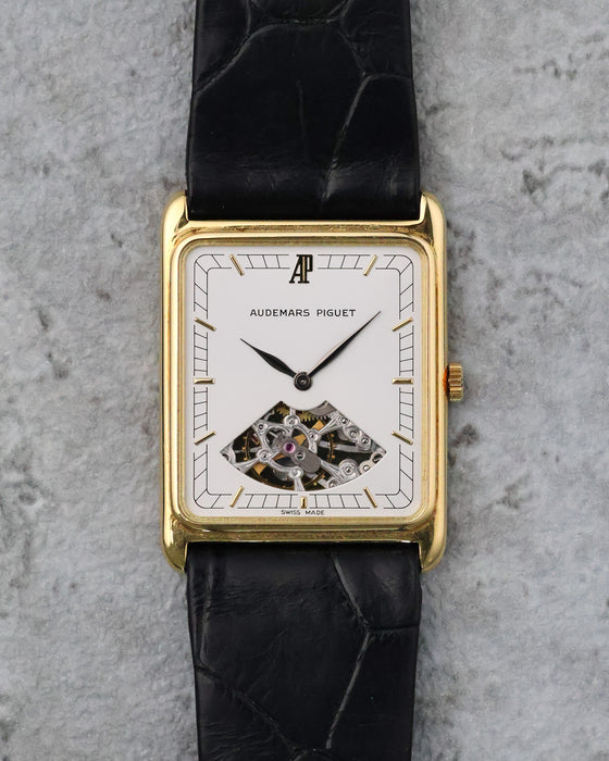 Front view of the Audemars Piguet showing its white dial, applied gold markers and exposed movement aperture at six.