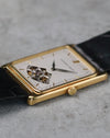 Low-angle side view showing the slim rectangular yellow gold case and crown.