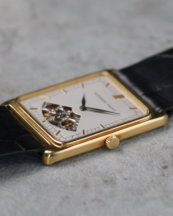 Low-angle side view showing the slim rectangular yellow gold case and crown.