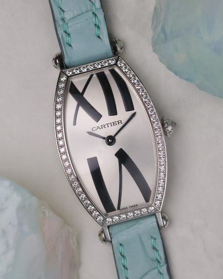 Angled dial view of the Cartier Tonneau WE400731 showing the curved white dial and diamond-set case.