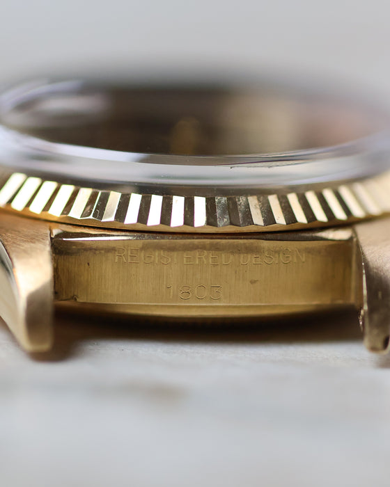 Macro side view of the Rolex Day-Date 1803 showing the serial engraving between the lugs and fluted yellow gold bezel.