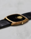 Side profile of the Piaget Ref. 9591 showing its engraved 18k yellow gold tonneau case and black leather strap.