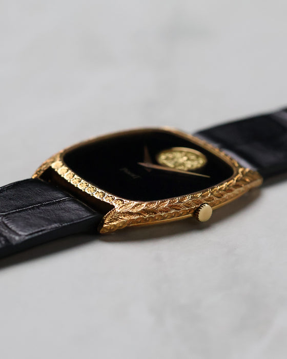 Side profile of the Piaget Ref. 9591 showing its engraved 18k yellow gold tonneau case and black leather strap.