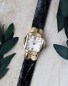 Patek Philippe Ref. 3017 yellow gold ladies watch photographed with foliage from a front angle.