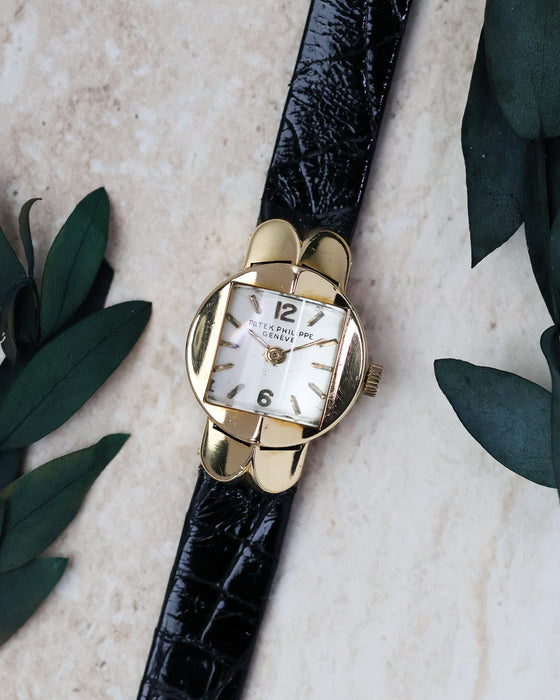 Patek Philippe Ref. 3017 yellow gold ladies watch photographed with foliage from a front angle.