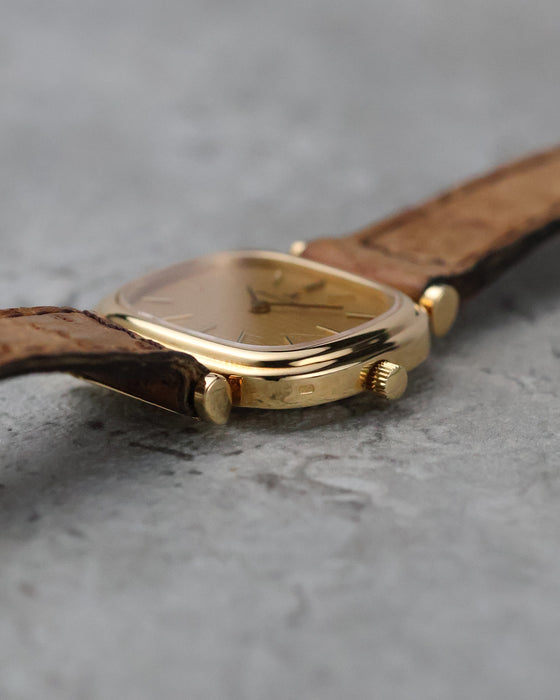 Crown-side profile showing the manual-winding crown and articulated gold lugs.