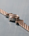 Angled profile highlighting the compact case, domed crystal, hinged lugs and vintage multi-link bracelet.