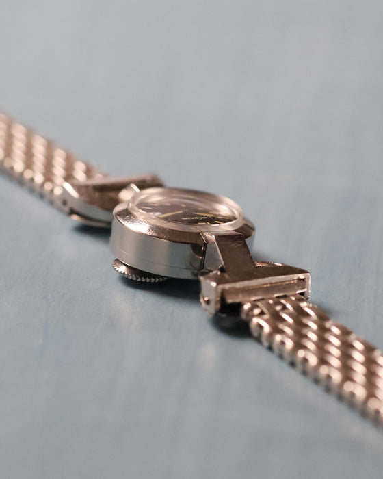 Angled profile highlighting the compact case, domed crystal, hinged lugs and vintage multi-link bracelet.