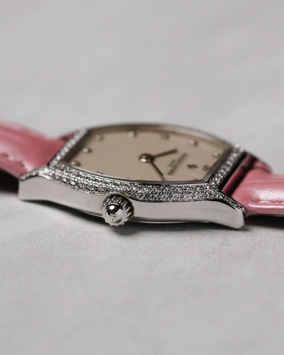 Side profile centred on the signed cabochon crown, showing the slim manual-wind case and polished white gold finish.