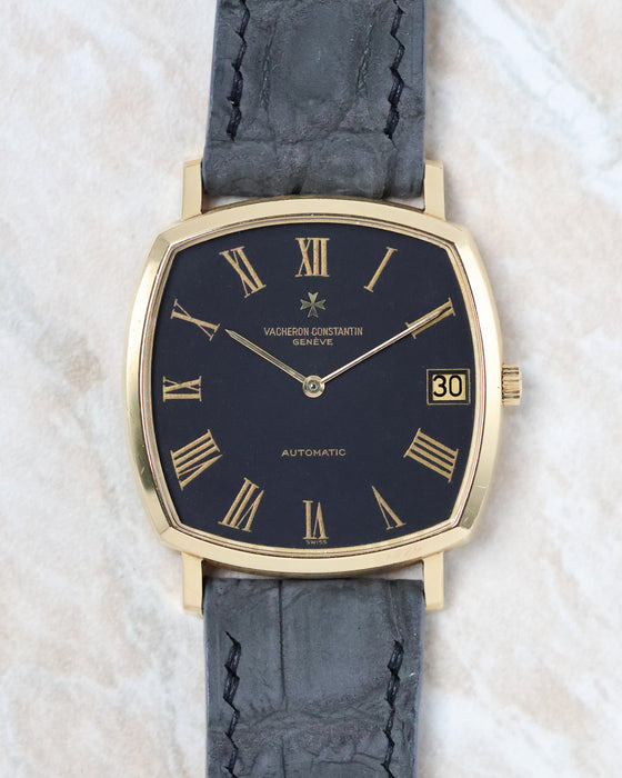 Front view of the Vacheron Constantin Ref. 7390 with a black dial, 18K yellow gold cushion case, and Roman numerals.