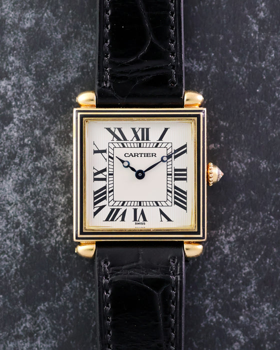 Front view of the Cartier Tank Obus Ref. 1630 with white Roman numeral dial, black enamel bezel and black leather strap.