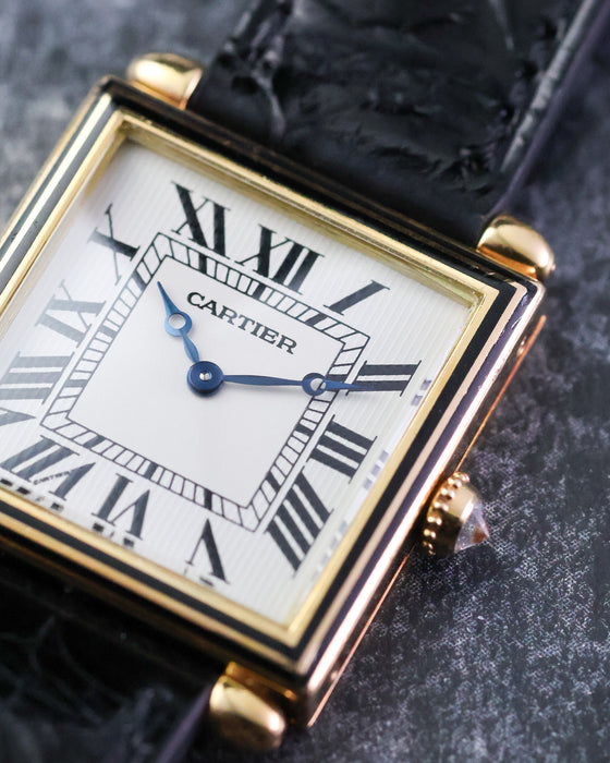 Macro photograph of the Cartier Tank Obus Ref. 1630 dial showing the Breguet hands, Roman numerals and black enamel bezel.