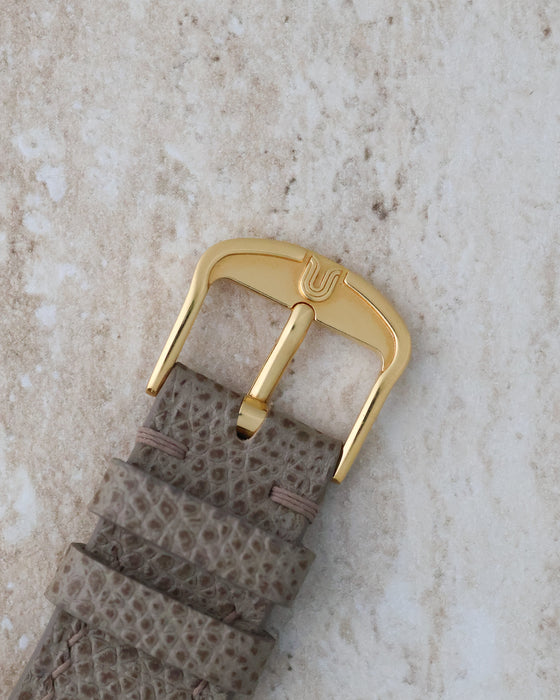 Original gold-tone Universal Genève signed buckle paired with the leather strap.