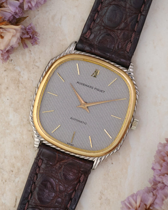 Angled dial view of the Audemars Piguet automatic framed by flowers, showing its two-tone rope case and textured silver dial.