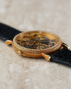 Angled view of the signed crown and detailed yellow gold case construction.