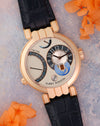 Angled view highlighting the silver dial, blue accents, day/night display and articulated rose gold lugs.